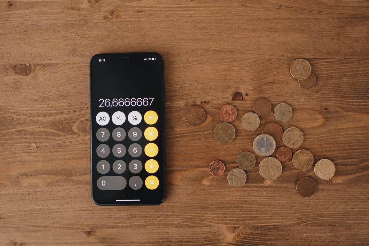 Smartphone avec calculatrice et pièces en euros pour calculer sa déduction fiscale du PER.