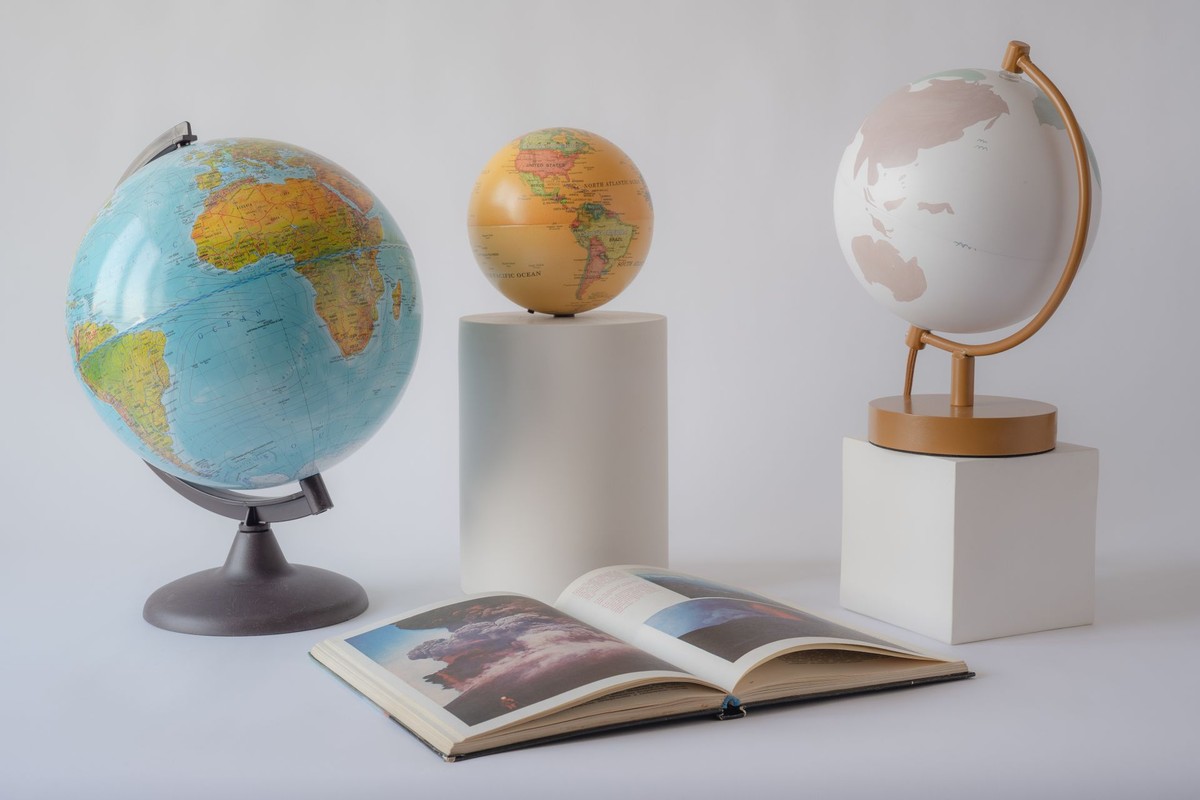 Trois globes terrestres de tailles différentes et un livre ouvert - choisir son premier ETF