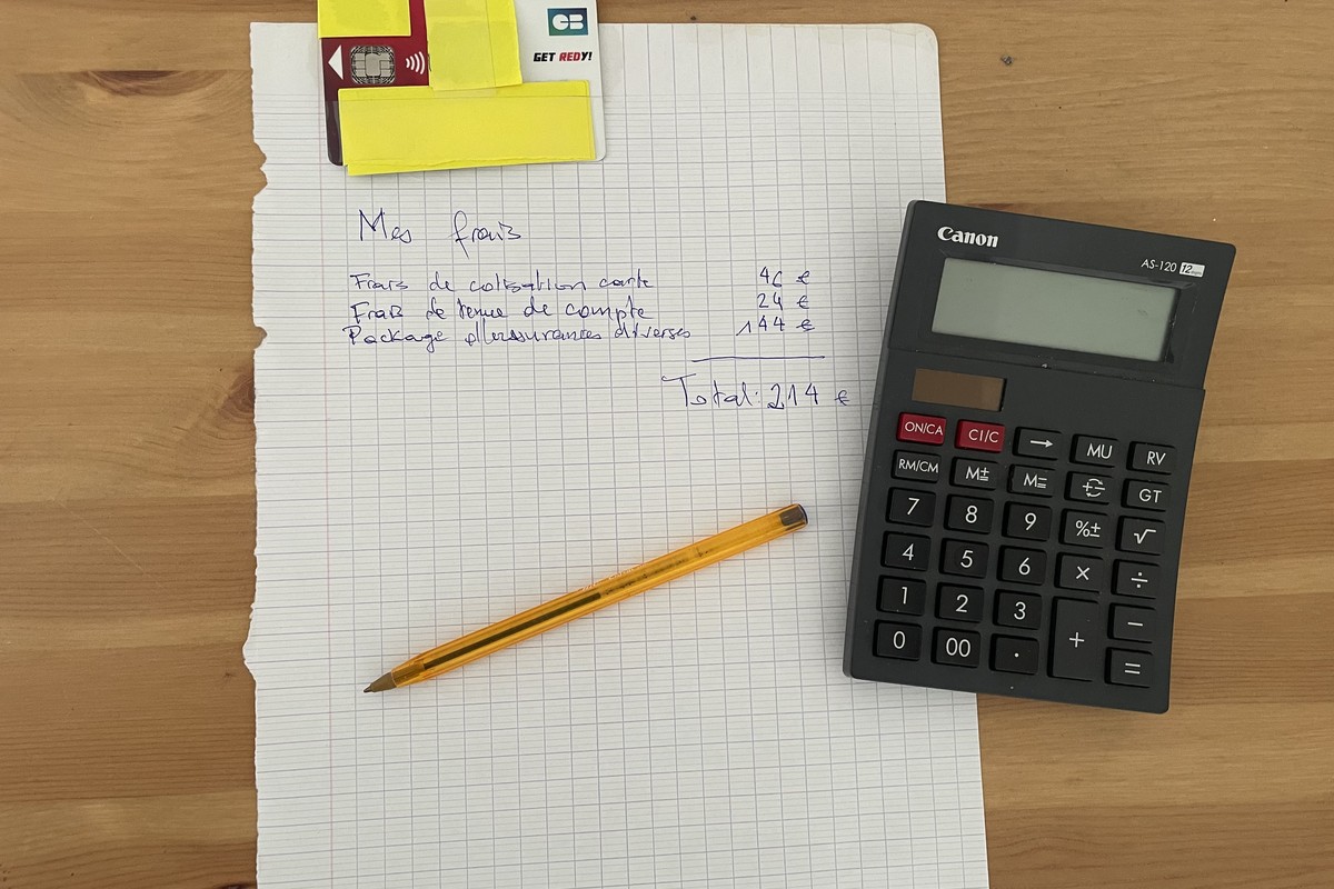 « Relevé manuscrit des frais bancaires annuels (cotisation carte, tenue de compte, package) à côté d'une calculatrice ».