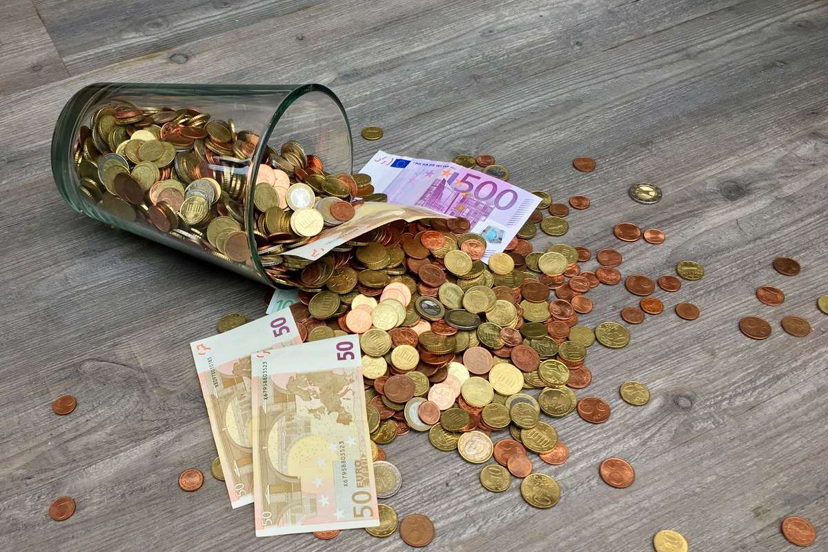 Bocal renversé avec pièces et billets, symbole de la fiscalité de l'épargne en 2026