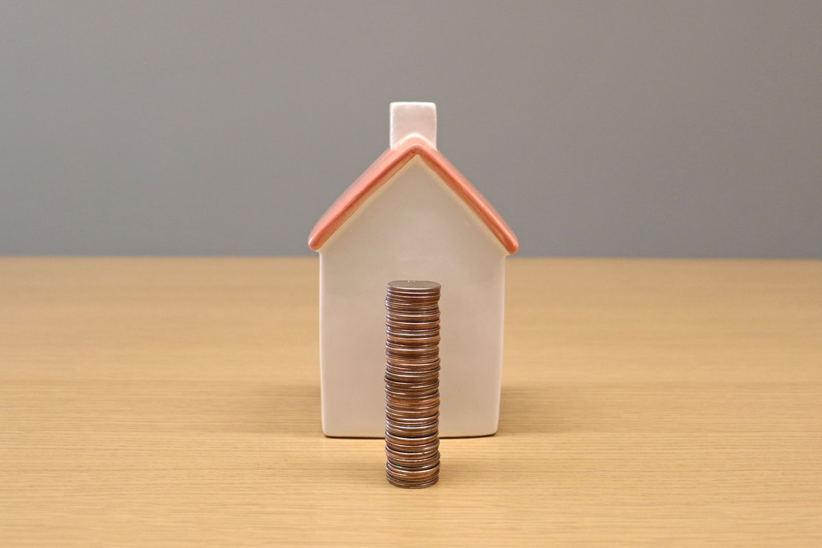 Maison miniature et pile de pièces illustrant le PTZ et les aides à l'achat